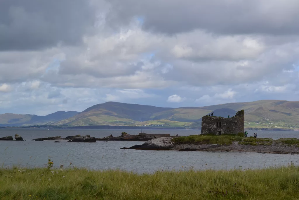 old castle in ireland by the water and surrounded by mountains