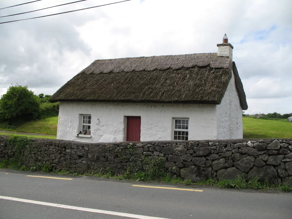 thatched Irish cottage with white walls and a red door